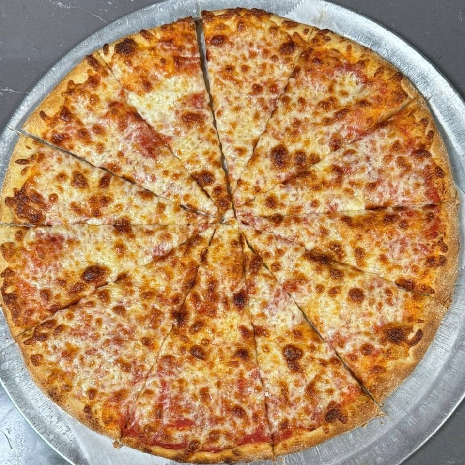 A whole cheese pizza, cut into many slices, on a metal pizza pan.